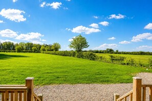 Un campo cubierto de hierba con una valla de madera y cielo despejado.