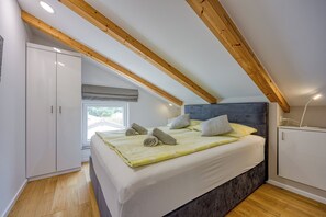 Une chambre à coucher avec un lit, des poutres en bois, une armoire et une fenêtre.