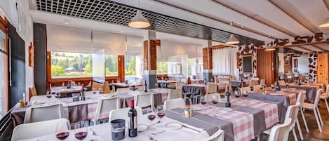 Un restaurant doté de nombreuses tables dressées pour le service, avec un décor intérieur moderne et de grandes fenêtres offrant une vue sur l’extérieur.
