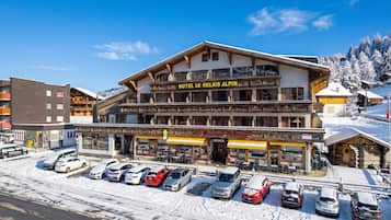 Ein Hotel im traditionellen alpinen Stil mit einem markanten Balkon und einem Schild mit der Aufschrift 'HOTEL LE RELAIS ALPIN'.