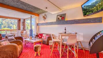 Ein modernes Wohnzimmer mit Kamin, Sitzecke und Esstisch mit Weingläsern.