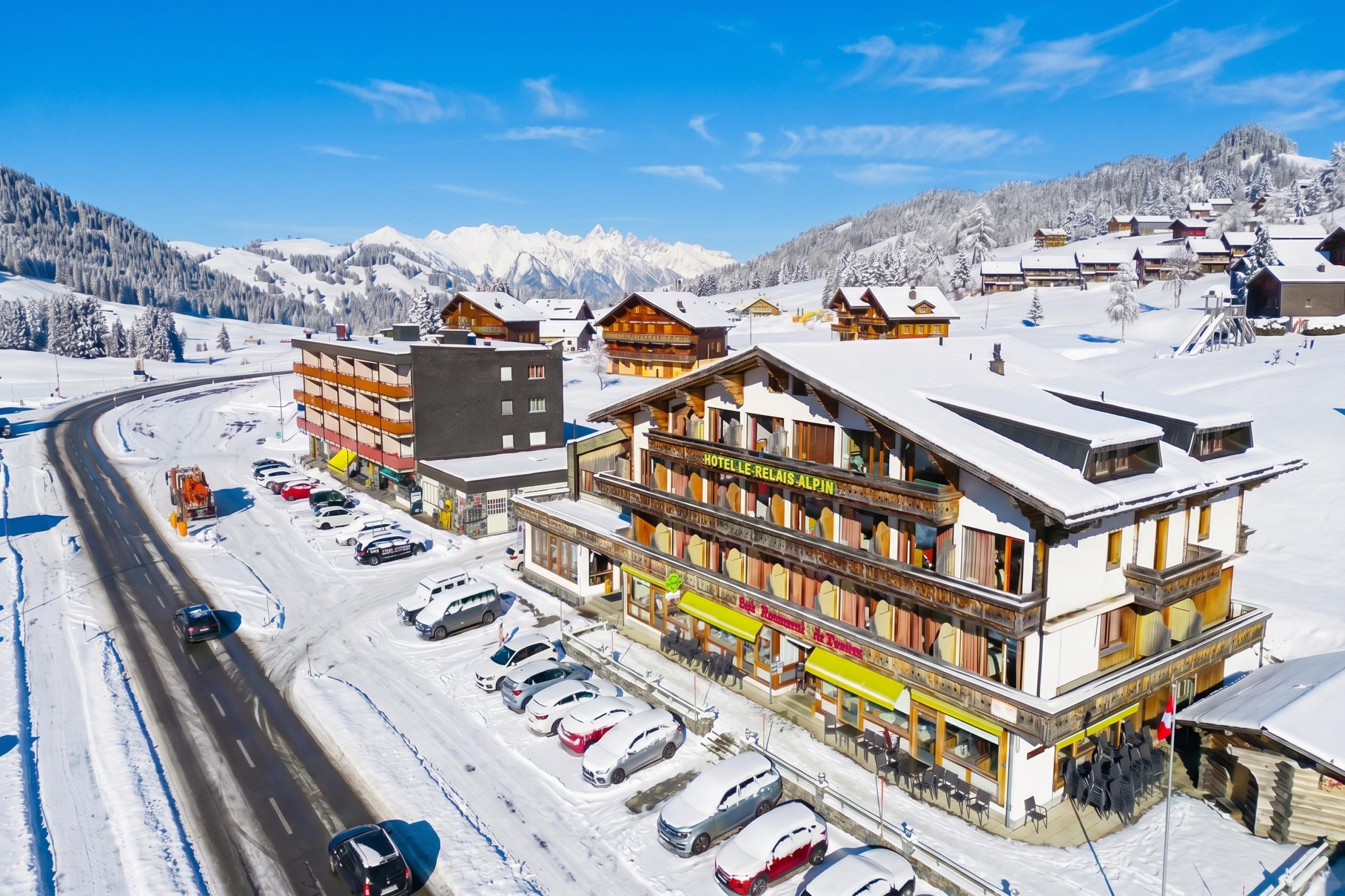 Un hôtel doté d’un télésiège, entouré de montagnes enneigées et offrant une vue sur un ciel dégagé.
