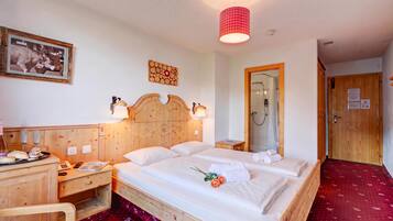 Ein Hotelzimmer mit einem hölzernen Bett, Nachttischen, einem Spiegel, einer Dusche und einem roten Teppich.