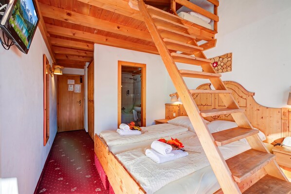 Une cabane en bois avec un escalier menant à un lit en mezzanine, une salle de bain avec douche et un téléviseur fixé au mur.