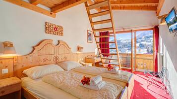 Ein Zimmer in einer Holzhütte mit zwei Betten, einer Leiter, einem Fernseher und Blick auf eine verschneite Landschaft.