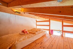 Ein Zimmer in einer Holzhütte mit einem Bett, einem Fenster und einer Deckenleuchte.