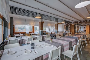 Un ristorante con diversi tavoli, sedie e lampadari.