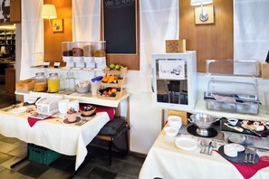 Montaje de un bufé de desayuno con diversas opciones de comida y bebidas.
