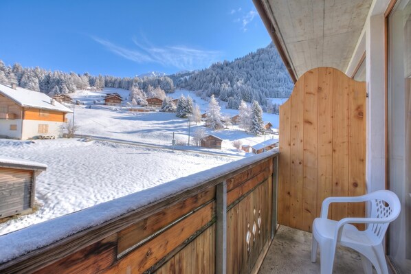 A wooden balcony with a view of a snowy landscape and houses. - Hotel Relais Alpin Twin Room & Balcony3 229, Les Mosses, Switzerland (Les Mosses)