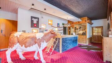A room with a large cow sculpture, a reception desk, and a red patterned carpet.