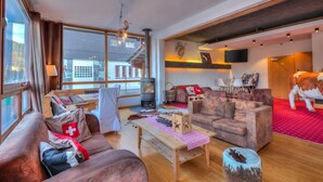 Una sala de estar moderna con chimenea, sofás de cuero, una mesa de centro de madera y una alfombra roja.