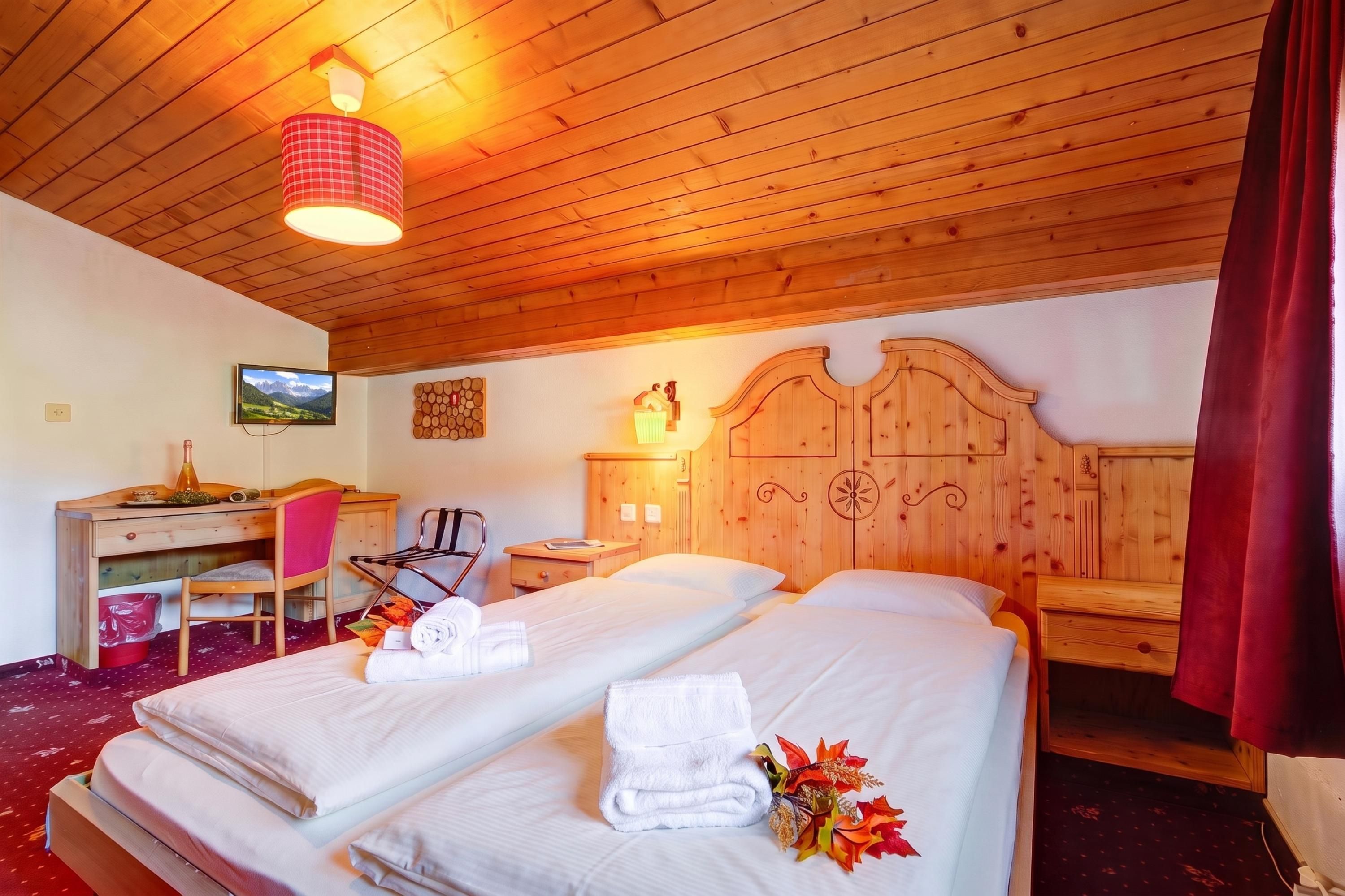 A hotel room with two beds, a desk, a chair, and a television on the wall.