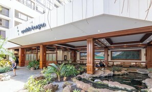 Ein Hotel mit Eingangsbereich, überdachtem Außenbereich, einem Teich mit Koi-Karpfen und einem großen Gemälde.