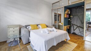 Un dormitorio moderno con cama, mesitas de noche, un armario y una puerta de vidrio que da a un baño.