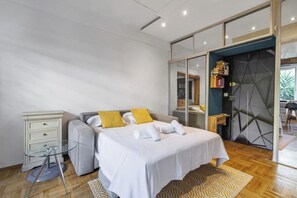 Ein modernes Schlafzimmer mit Bett, Nachttischen, einem Kleiderschrank und einer Glastür zum Badezimmer.