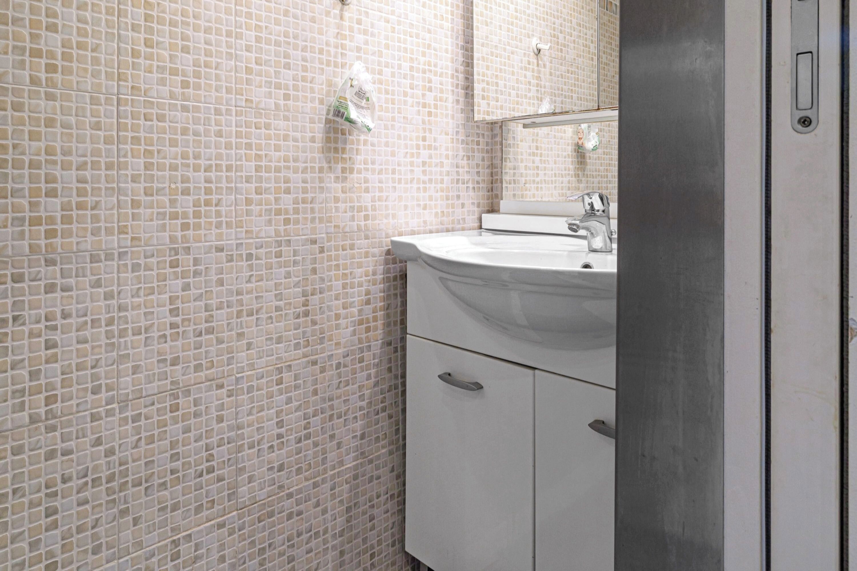 Un bagno con parete piastrellata, un lavandino e uno specchio.