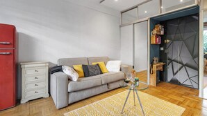 Una sala moderna con un sofá, una mesa de centro de vidrio y un refrigerador rojo.