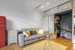 Ein modernes Wohnzimmer mit einer Couch, einem Glastisch und einem roten Kühlschrank.