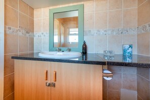 A bathroom with a wooden cabinet, a sink, and a mirror. - Luxury Riverside Views | Balcony | Pool (Velddrif)