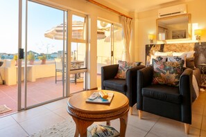 A cozy living room with a sofa, a small round table, and a sliding glass door leading to a balcony. - Luxury Riverside Views | Balcony | Pool (Velddrif)