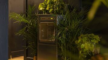 A modern kitchen with a built-in refrigerator, surrounded by lush green plants.