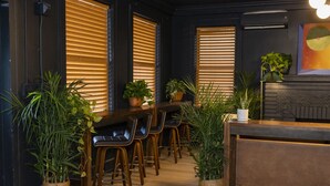 Een bar met houten stoelen en tafels, omringd door plantenpotten.