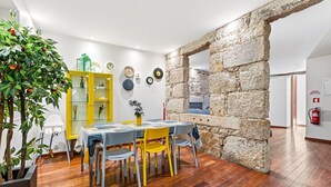 Zona pranzo con parete in pietra, pavimento in legno e un armadietto giallo con ante in vetro.