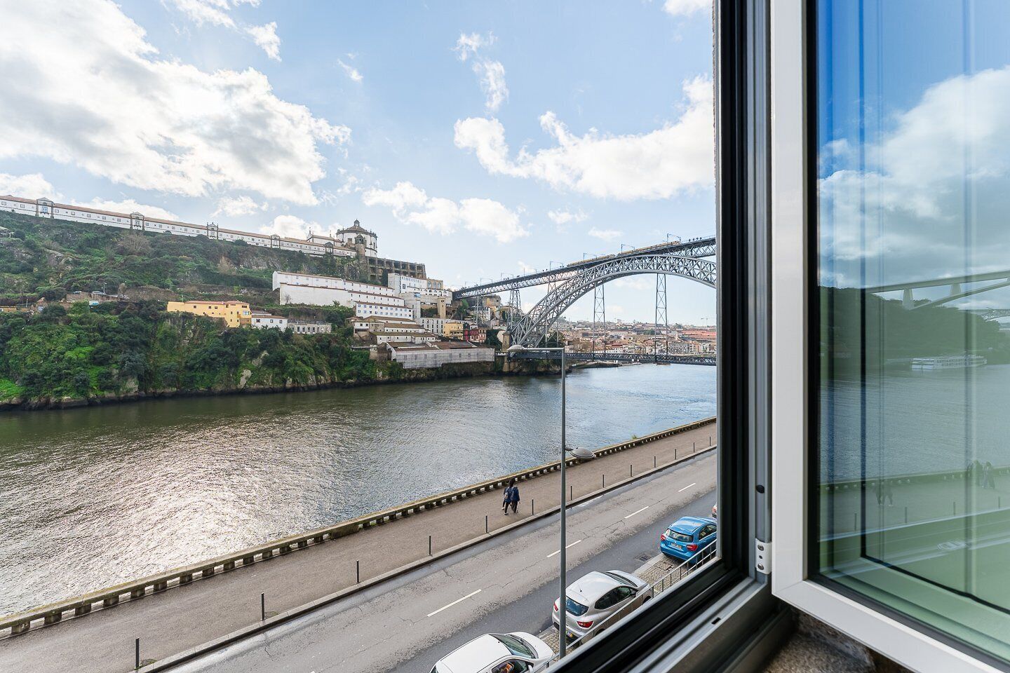 Vista de un río con un puente, edificios y una carretera con automóviles.
