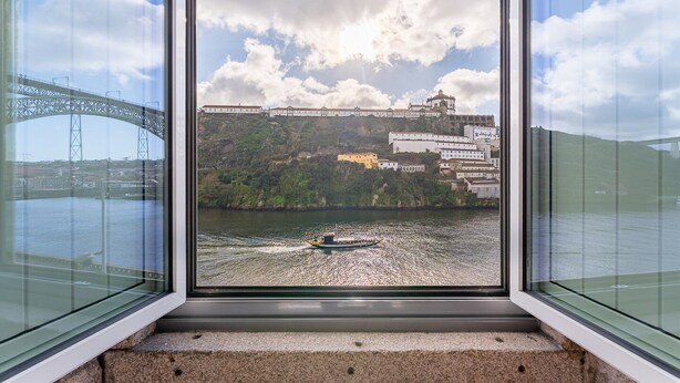 Vista dalla finestra su un fiume con un ponte e edifici sull'altra sponda.