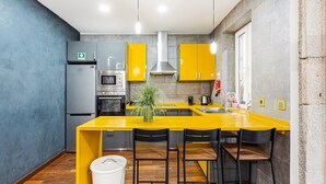 Una cucina moderna con isola gialla, elettrodomestici in acciaio inossidabile e parete grigia.