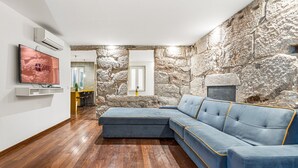 Un soggiorno moderno con un divano componibile, una parete in pietra, un caminetto e una TV a parete.