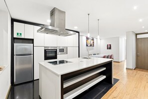 Una cocina moderna con refrigerador, horno y microondas de acero inoxidable, una isla grande con pileta e iluminación colgante.