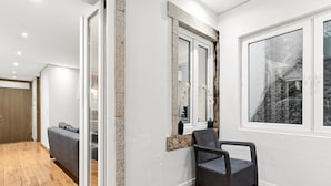 A modern interior with a grey sofa, a wicker chair, a large mirror, and a window with a view. - GuestReady - Urban comfort with Douro River view (Porto)