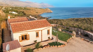 A coastal house with a tiled roof, a satellite dish, and a stone pathway leading to the sea. - Villa Scogliera with sea view and pool (Castellammare del Golfo)