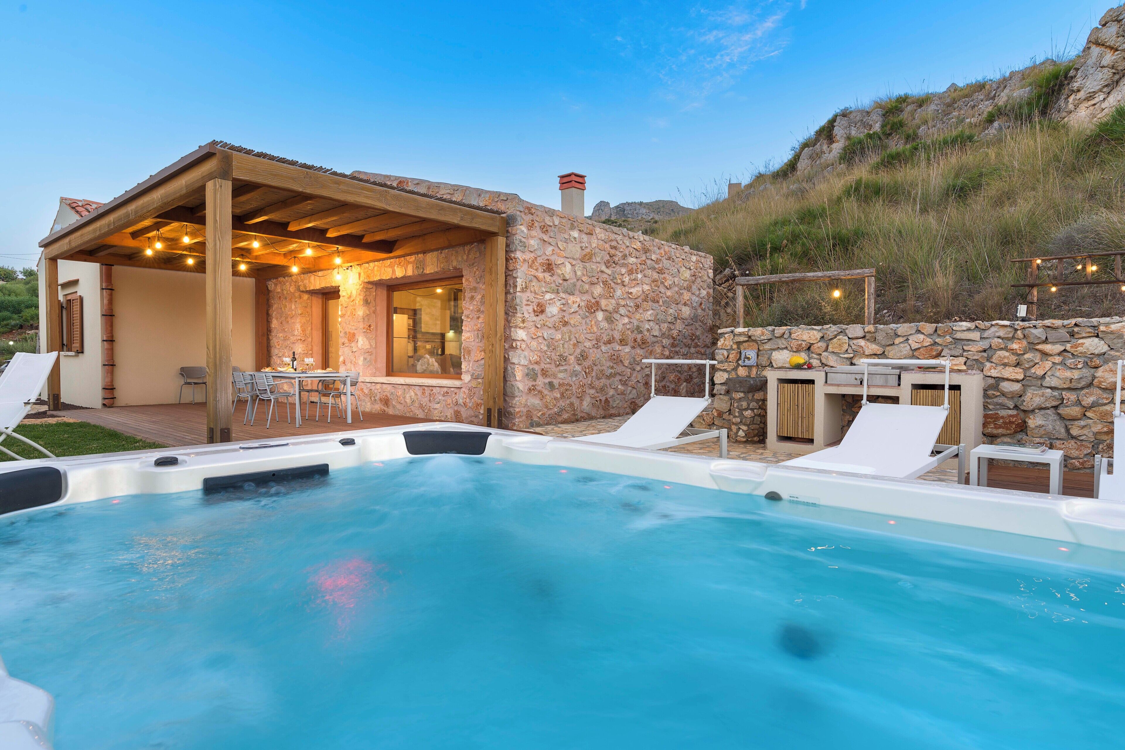 A stone house with a hot tub and outdoor seating.
