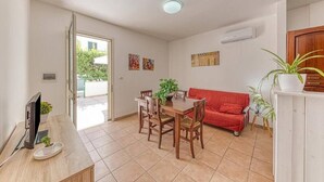 Um espaço de estar compacto com área de jantar, um sofá vermelho e uma TV sobre uma mesa de madeira.