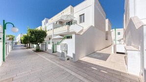 Um edifício moderno com telhado plano, escadaria e pequena área externa com um banco.
