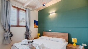Een hotelkamer met een bed, nachtkastje, lamp en raam met gordijnen.