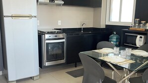 Une cuisine moderne équipée d’un réfrigérateur, d’une cuisinière, d’un four et d’un four à micro-ondes. On y trouve une table à manger avec des chaises et une fenêtre au-dessus de l’évier.