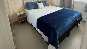 Une chambre bien rangée, avec un grand lit, une table de chevet et une fenêtre avec des rideaux.