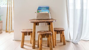 Een ronde houten tafel met een geweven mand erop, omringd door bijpassende krukken.