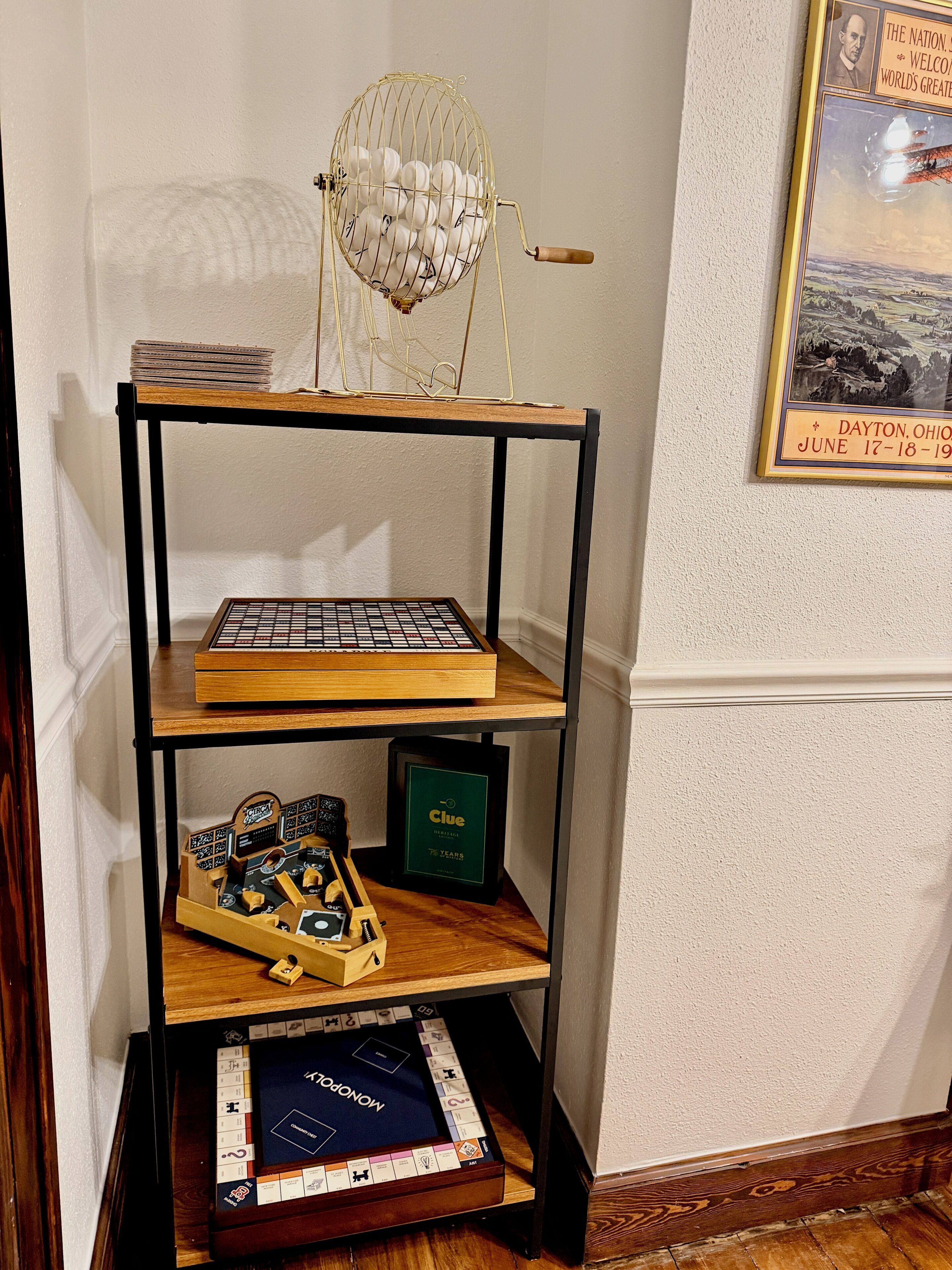 Une étagère en bois avec des jeux de société, un tableau encadré et un petit globe terrestre.
