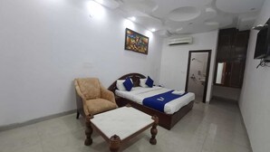 A bedroom with a bed, a chair, and a small table. - Taj homes - A Unit of Sahni's Villa (Gurugram)