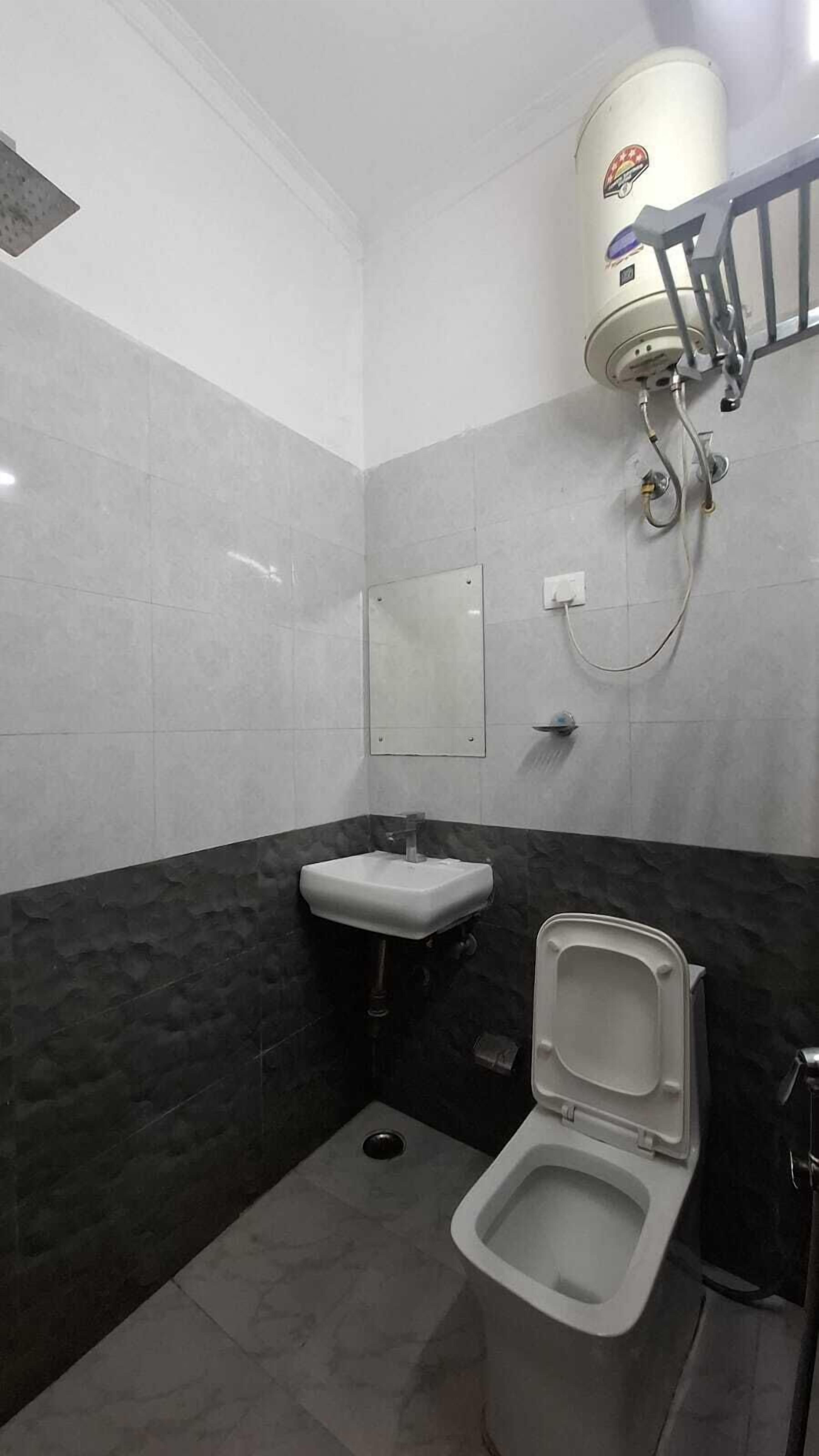 Un baño pequeño y moderno con inodoro, lavamanos y un dispensador de papel higiénico en la pared.