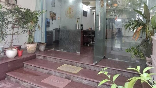 A reception area with a glass door, a ceiling fan, and potted plants. - Taj homes - A Unit of Sahni's Villa (Gurugram)