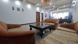 A conference room with a large table, four sofas, and a chandelier. - Taj homes - A Unit of Sahni's Villa (Gurugram)