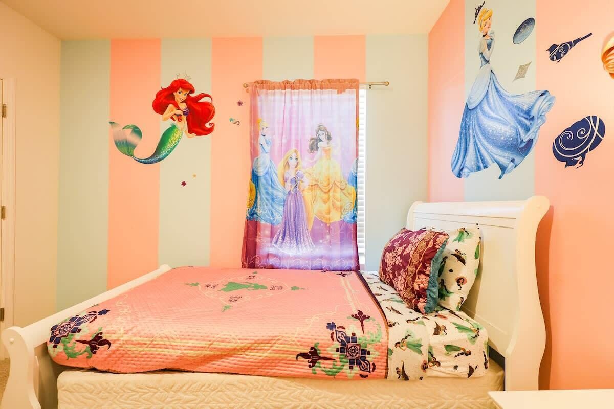 A bedroom with a bed, a window with a curtain, and wall decorations.
