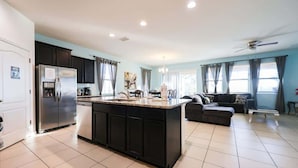 A modern kitchen with a central island, dark cabinetry, and a refrigerator. - Luxury Resort Pool House 6B5.5B perfect for family (Davenport)