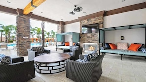 An outdoor lounge area with wicker furniture, a fire pit, a pool, and a stone wall. - Luxury Resort Pool House 6B5.5B perfect for family (Davenport)
