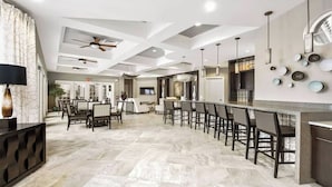 A modern kitchen with a bar area, dining chairs, and a ceiling fan. - Luxury Resort Pool House 6B5.5B perfect for family (Davenport)